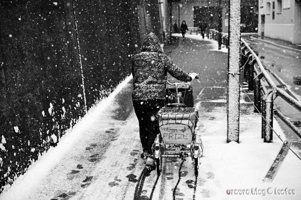 雪の中を傘なしで歩く人。