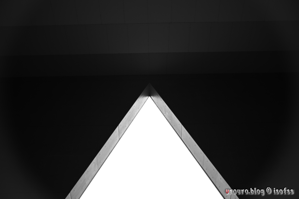 奇抜な形をした三角形の建物の入口。モノクロ写真で陰影のトーンを表現。