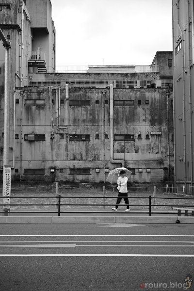 廃墟の壁の前を歩く通行人を撮影。Viltrox AF 50mm F2 AIR & Nikon Zf で撮影。ピクチャーコントロールはモノクローム。